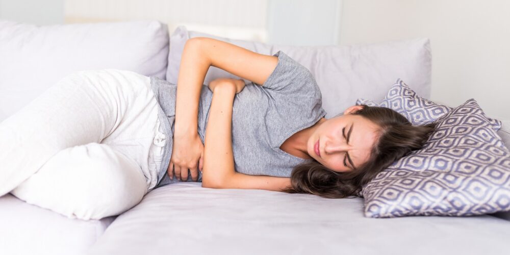 Fotografie: Žena má bolesti břicha a leží na posteli