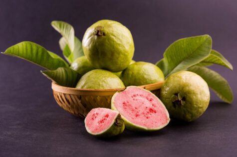 Fresh Red Guava fruit also known as Amrood in Hindi and Peru in Marathi, Served in a basket as a whole or slices over colourful background. Selective focus