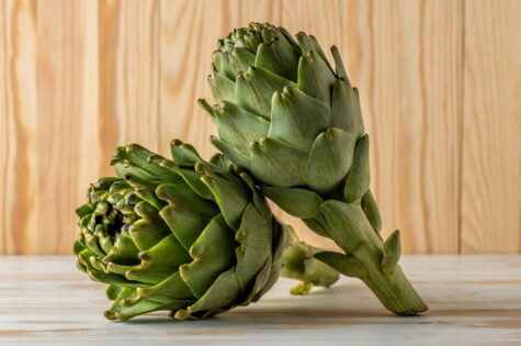 Ripe organic artichokes on a white wooden table. Vegetable background.