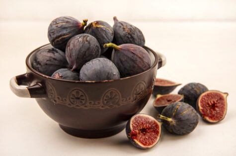 top view of sweet black mission figs on a bowl on a white background